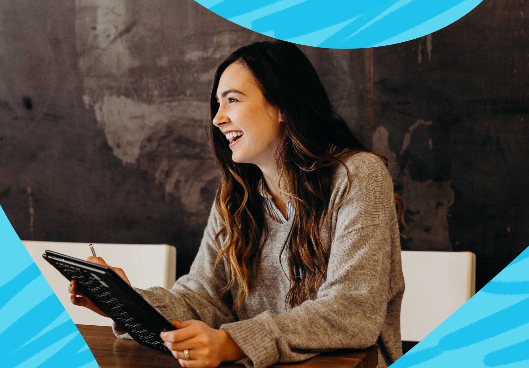 Smiling woman sitting at a desk, holding a tablet