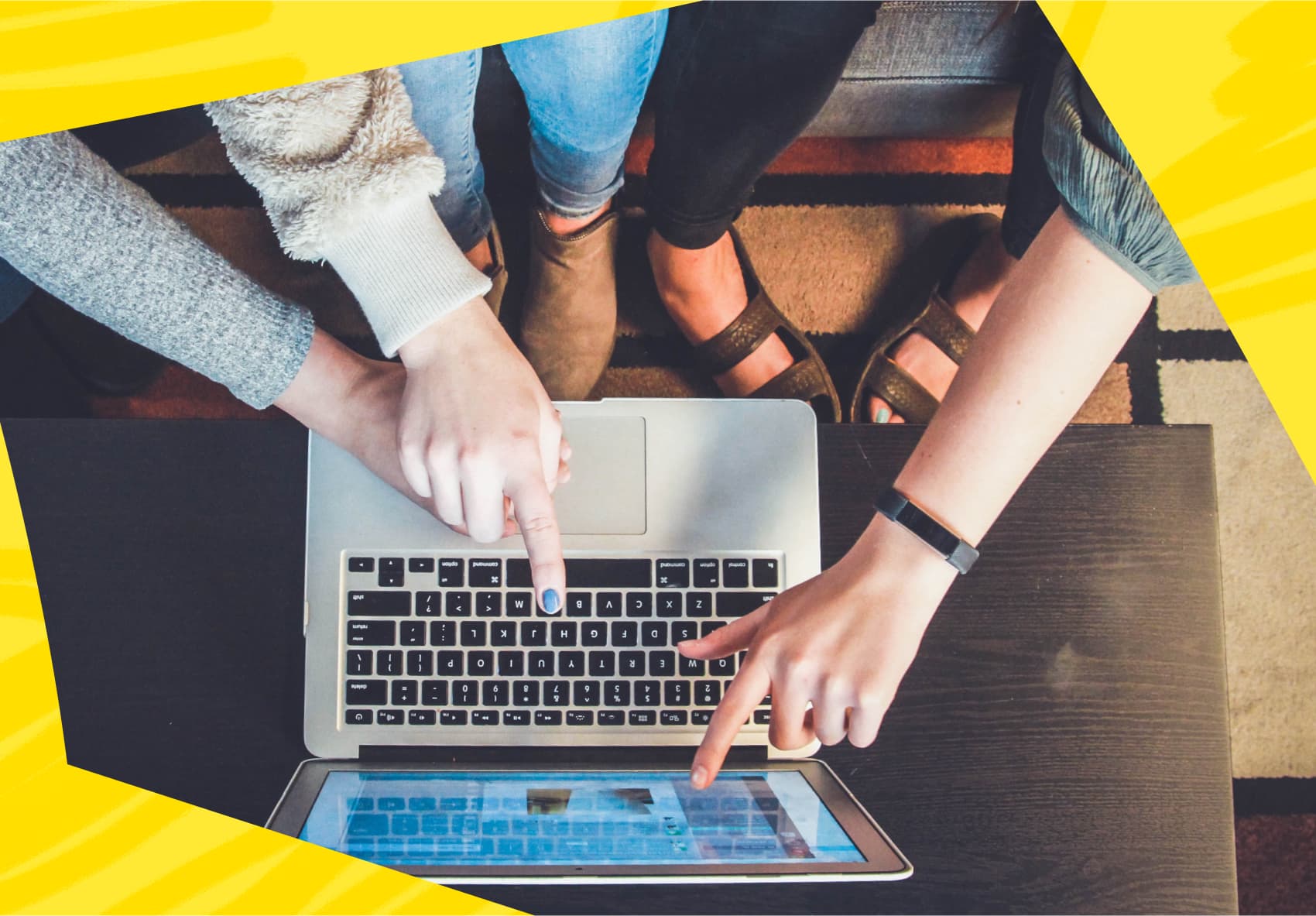 Three hands pointing at laptop computer screen